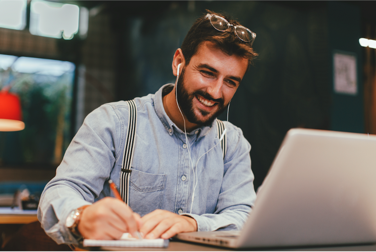 Smiling young man taking notes of a video call